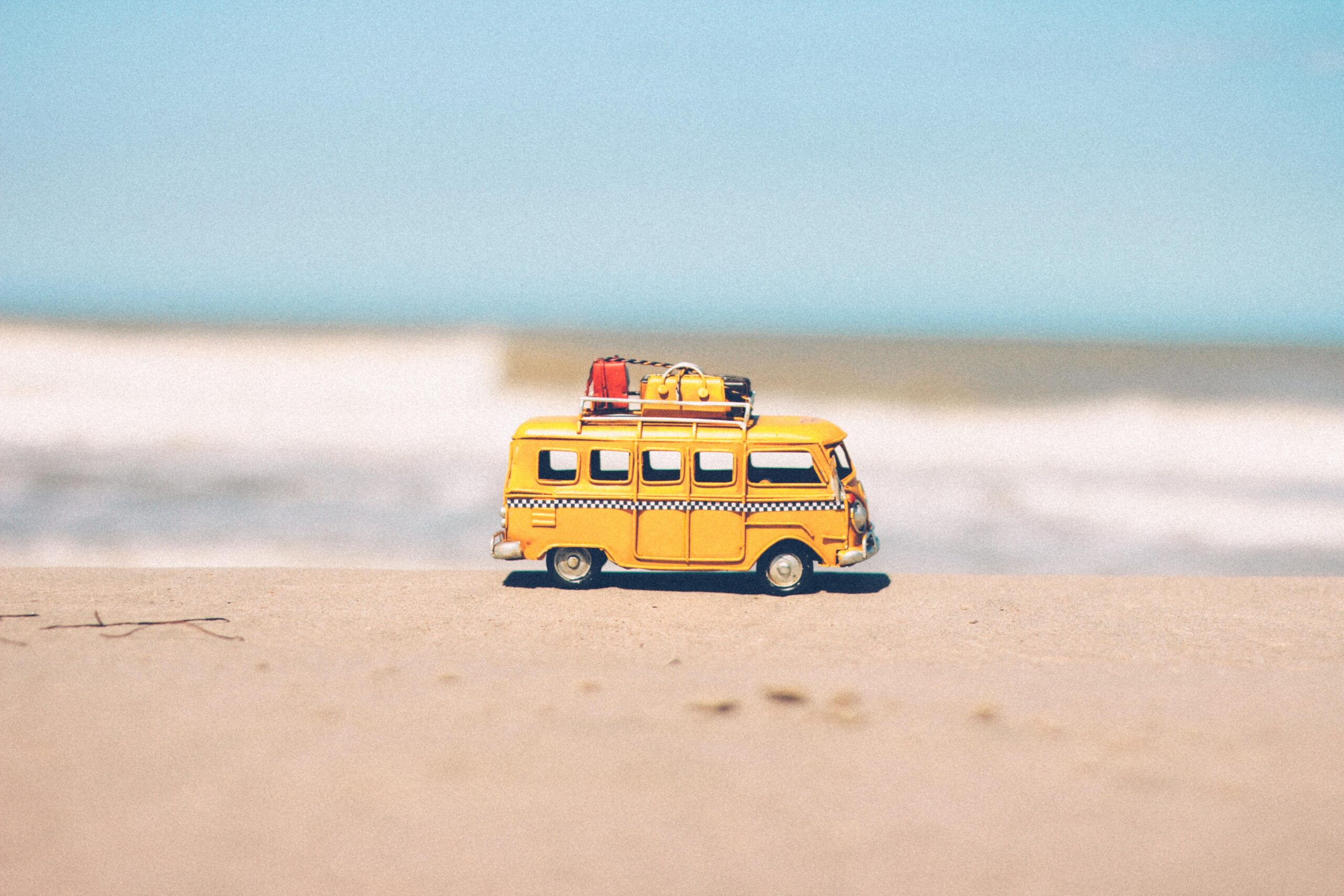 A small yellow bus with luggage on top to show that someone is moving locations. This is for an article about how to research your new home's location